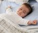 Спящо бебе в легло с бяло одеяло и син чаршаф